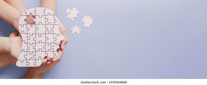Adult and children hands holding brain with puzzle paper cutout, autism, memory loss, dementia, epilepsy and alzheimer awareness, world mental health day, world Parkinson day concept - Shutterstock ID 1935964840