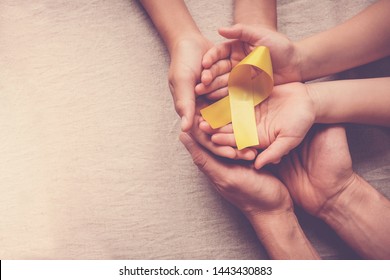adult and children hands holding yellow gold ribbon, Sarcoma Awareness, Bone cancer, childhood cancer awareness, September yellow, World Suicide Prevention Day