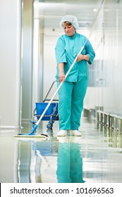 Adult cleaner maid woman with mop and uniform cleaning corridor pass floor of pharmacy industry factory or clinic