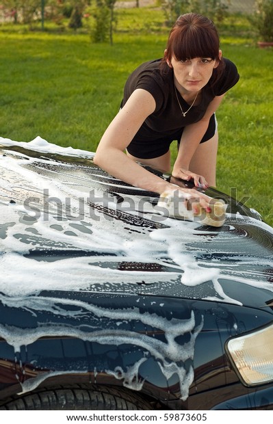 Adult cleaning her car\
outside