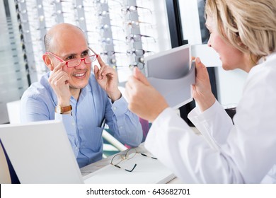 Adult Consultant And Male Customer Choosing Glasses In Optics Store