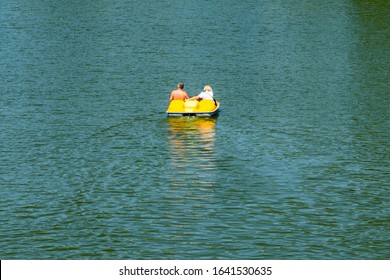 Adult couple driving yellow catamaran on river