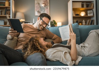 Adult couple man and woman Caucasian husband and wife in a relationship real book hold books on the sofa bed at home in the apartment reading leisure bonding family concept real people copy space - Powered by Shutterstock