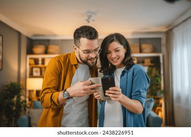 Adult couple man and woman husband wife have a cup of coffee use mobile phone search internet social network happy smile - Powered by Shutterstock