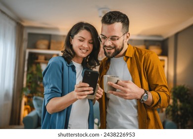 Adult couple man and woman husband wife have a cup of coffee use mobile phone search internet social network happy smile