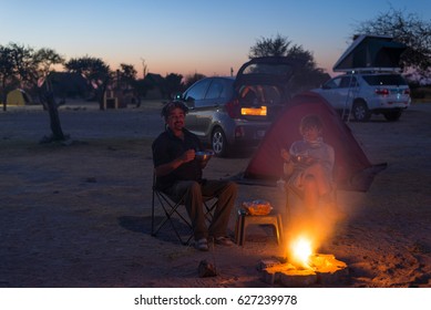 Adult couple relaxing in camping site by night. Adventure in National Park, South Africa. Burning camp fire and tent in the background. Toned image.
 - Powered by Shutterstock