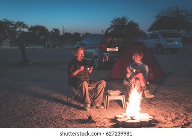 Adult couple relaxing in camping site by night. Adventure in National Park, South Africa. Burning camp fire and tent in the background. Toned image.
 - Powered by Shutterstock