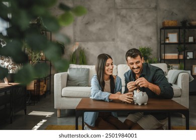 Adult couple save money coins in the piggy bank at home - Powered by Shutterstock