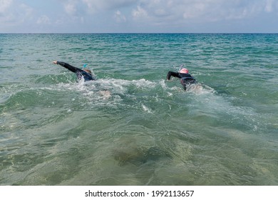 Adult Couple Swimming With Wetsuit In The Sea.