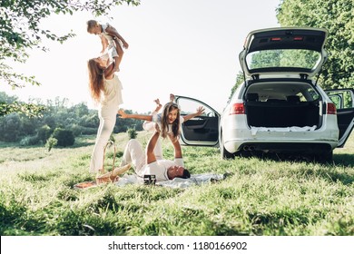 Adult Couple With Their Little Children Having Picnic In The Park Outside The City, Family Weekend Concept, Four People Enjoying Summer