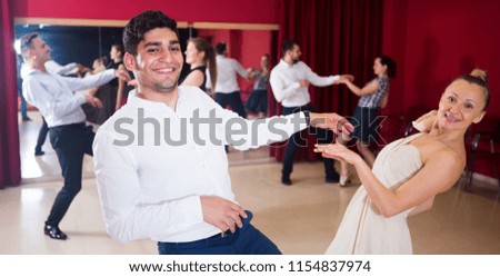 Adult dancing couples enjoying active dance in modern studio