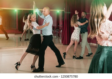 Adult Dancing Couples Enjoying Foxtrot In Dance Studio

