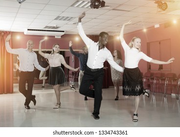 Adult Dancing Couples Enjoying Rhythmic Tap Dance In Dance Studio

