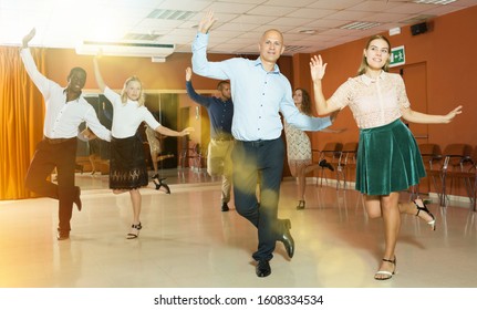 Adult Dancing Couples Enjoying Rhythmic Tap Dance In Dance Studio

