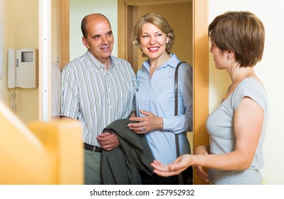 Adult Daughter Greeting Smiling Elderly Parents At Threshold 