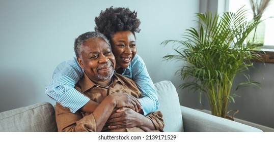 Adult daughter visits senior father in assisted living home. Portrait of a daughter holding her elderly father, sitting on a bed by a window in her father's room.  - Shutterstock ID 2139171529