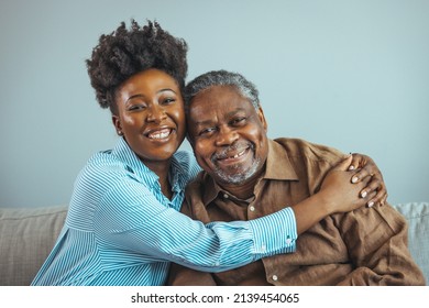 Adult Daughter Visits Senior Father In Assisted Living Home. Portrait Of A Daughter Holding Her Elderly Father, Sitting On A Bed By A Window In Her Father's Room. 