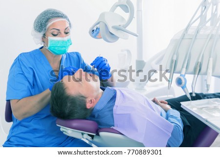 adult dentist checking teeth of patient male sitting in medical center 