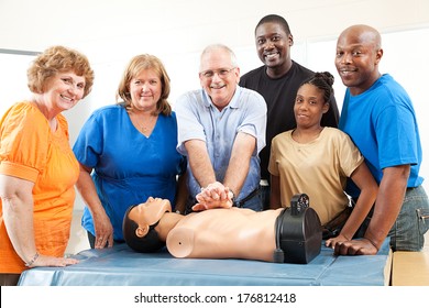 Adult Education Class On CPR And First Aid.  Students And Teacher With Dummy.  