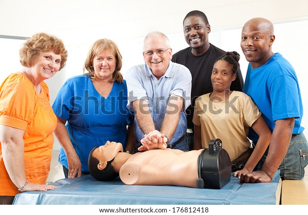 Adult education class on CPR and First Aid. \
Students and teacher with dummy. \
