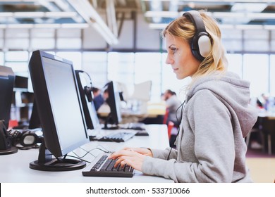 Adult Education, Student In Headphones Working On Computer In The Library Or Classroom Of University