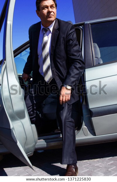 adult, elderly, solid, a man gets out of\
the car, on the background of a modern\
building