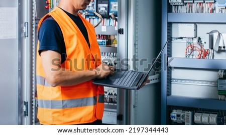Adult electrician builder engineer testing and screwing equipment in fuse box and repairing of modern electricity power station. Automatic control cabinet