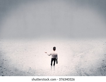An adult elegant businessman standing in the middle of nowhere in empty grey concrete space background concept