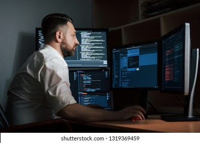 Adult Experienced Programmer. Bearded Man In White Shirt Works In The Office With Multiple Computer Screens In Index Charts.