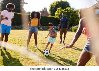 Adult Family Playing Football With Young Son In Garden