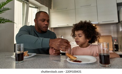 Adult Father Giving Pizza Slice To His Little Son During Having Lunch Or Dinner At Table At Home Kitchen. Unhealthy Eating. Young Black Family Lifestyle And Relationship. Fatherhood And Parenting