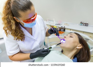 Adult female dentist treating patient woman teeth. Medicine, dentistry and healthcare concept. - Shutterstock ID 1159619260