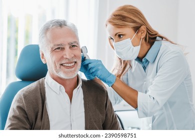 Adult female doctor examining patient's ear with otoscope. Laryngitis otitis barotrauma treatment prevention. Deafness observation. Geriatrics - Powered by Shutterstock