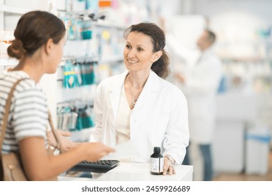 Adult female pharmacist giving prescription medicine to young female buyer at pharmacy - Powered by Shutterstock