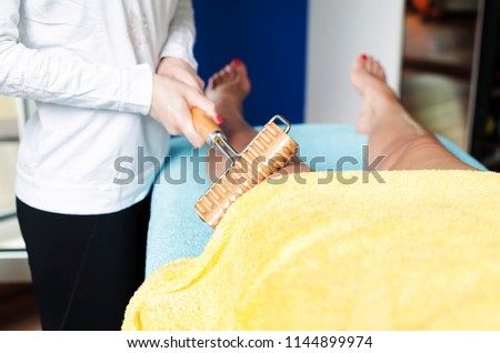 Adult female receiving maderotherapy treatment at beauty salon.