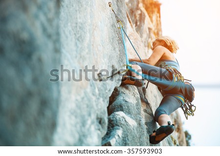 Adult female rock climber on vertical flat wall with poor relief - side view, close-up. 