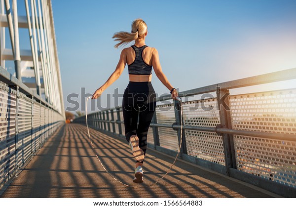 Adult fitness woman skipping the\
rope outside on bridge. Concept of fitness and\
lifestyle.