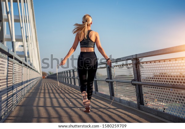 Adult fitness woman skipping the\
rope outside on bridge. Concept of fitness and\
lifestyle.