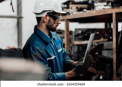 Adult Foreman Working On Digital Laptop In Aluminum Mill. Engineer Reading And Check A Plan On A Laptop While Being In A Warehouse.