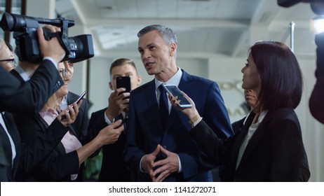 Adult formal man of government deputy talking to group of journalists and giving interview with smile looking excited with success