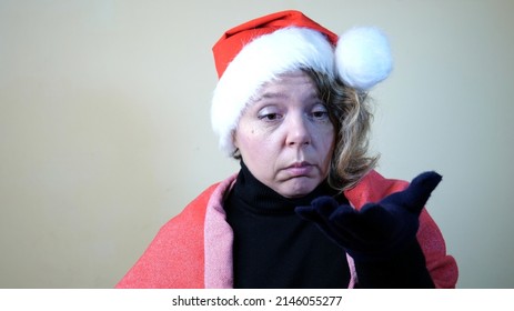 An Adult Forty-year-old Woman In A New Year's Red Cap. Portrait Of A Sad Blonde Woman. Christmas