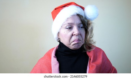 An Adult Forty-year-old Woman In A New Year's Red Cap. Portrait Of A Sad Blonde Woman. Christmas