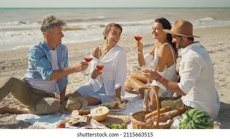 Adult Friends making toast celebration dinner party, drinking wine, eating mediterranean food, sitting by seashore - Powered by Shutterstock