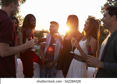 Adult Friends Socialising At A Party On A Rooftop At Sunset