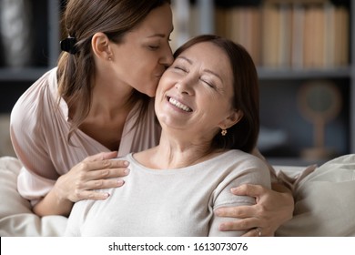 Adult Girl Child Kiss Overjoyed Middle-aged Mom Relaxing Together On Sofa In Living Room, Happy Grownup Daughter Rest Enjoy Time At Home With Senior Mother, Showing Love And Care, Bonding Concept