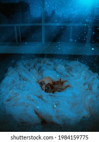 Adult Girl Princess Is Sleeping On Floor In Luxury Long Dress. Dark Room Filled With Magic Moon Light, Space Stars Shining, Night City View From Window. Fairy Woman Is Bewitched Queen Sleeping Beauty