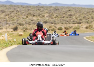 Adult Go Kart Racers On Track.  Five Carts In A Row Heading Into Turn.