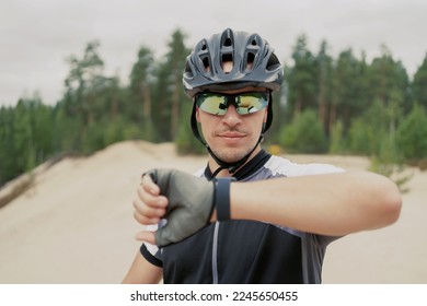 An adult guy on a mountain bike in a helmet uses a bicycle computer on a fitness watch, a navigator in a forest without Internet. - Powered by Shutterstock