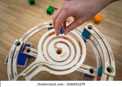 Adult Hand Purposefully Holds A Ball Over A Marble Run Toy