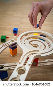 Adult Hand Purposefully Holds A Ball Over A Marble Run, Toy